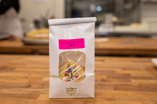 Window bag labeled "Specialty Strawberry Funfetti (NF) - Half-Dozen 18-S" with specialty strawberry funfetti hamantaschen visible through the window.
