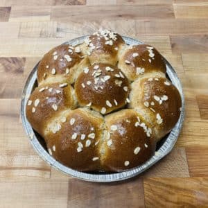 Honey Wheat Pull-Apart Rolls; 8 brown bread rolls in a pie tin with a topping of rolled oats, on a wood table top