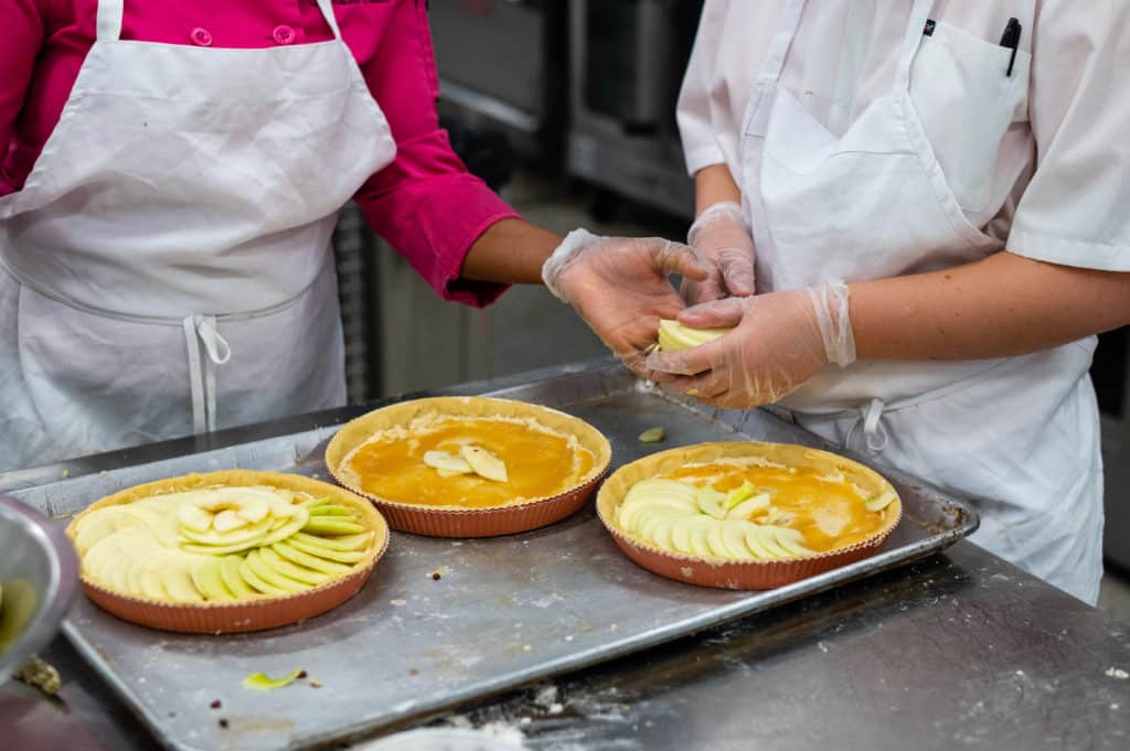 Instructor giving student a hand making apple almond tarts