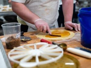 Student hand spreading jam on a circle of rugelach dough