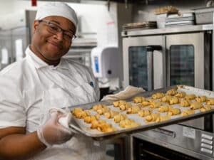 Student smiling, with cookie sheet full of baked rugelach