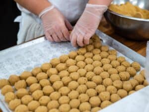 Student hands arranging scooped balls of cookie dough