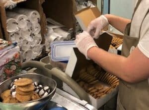 Student hands weighing cookies and boxing them