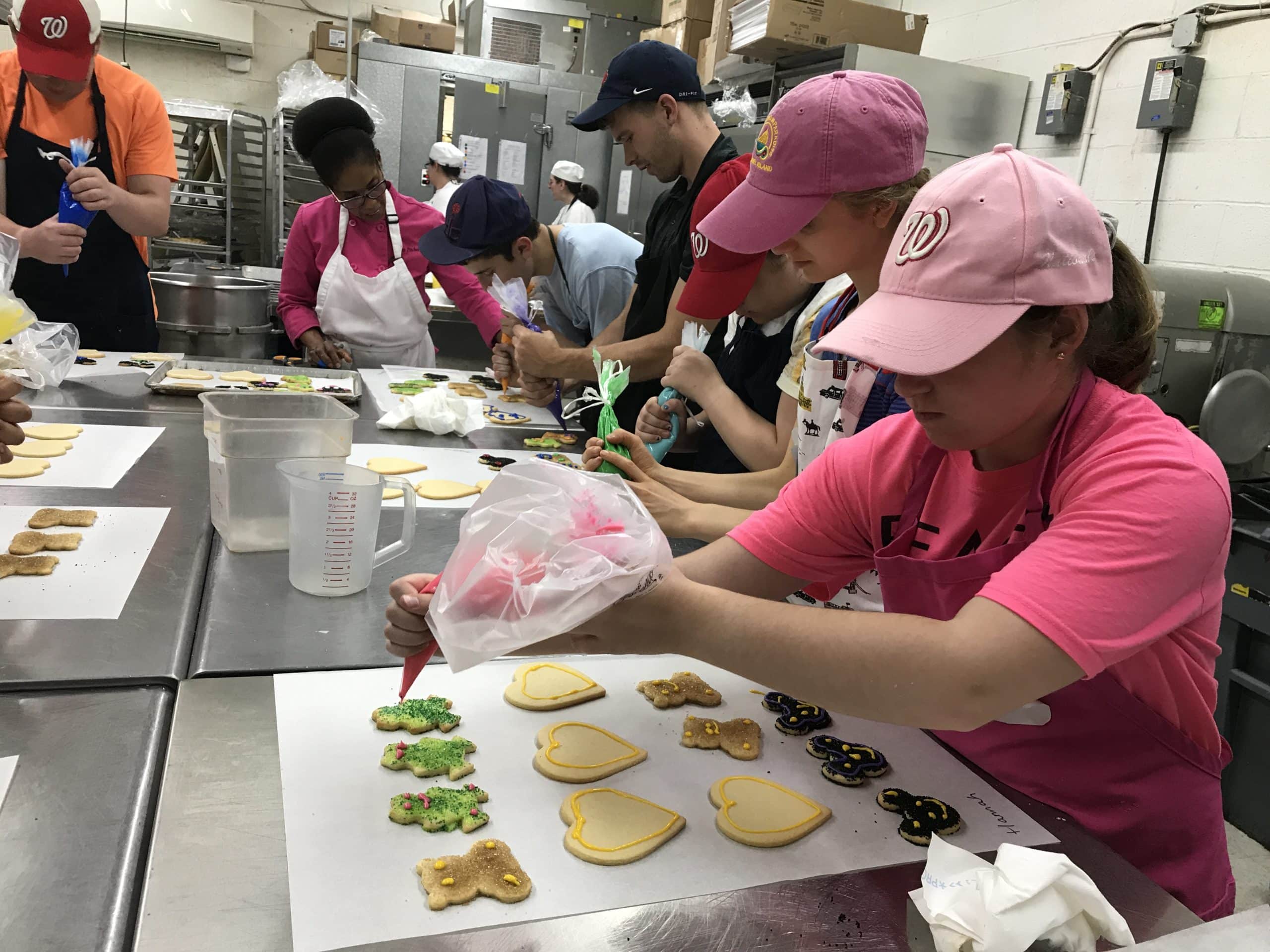 Teen program students decorating cookies and instructor