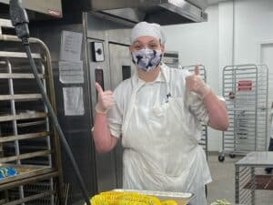 Student wearing mask but smiling and giving thumbs up