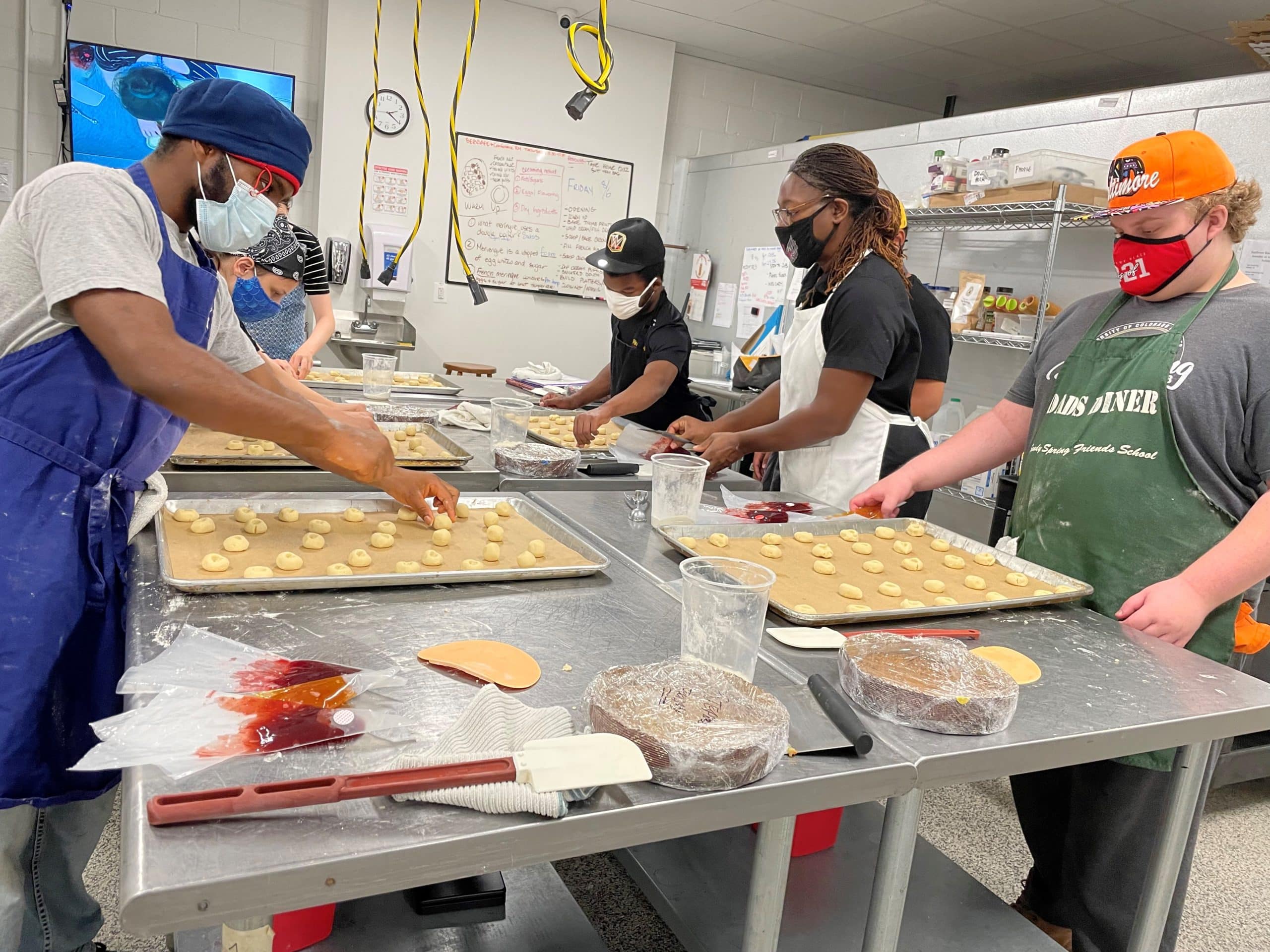 Teen students preparing jam thumbprint cookies with instructor