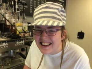 Student smiling while at an espresso machine