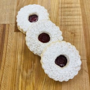 Three Linzer Cookies on a wood countertop