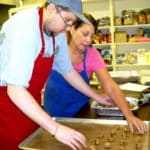 Instructor working with a student to lay out cookies to bake