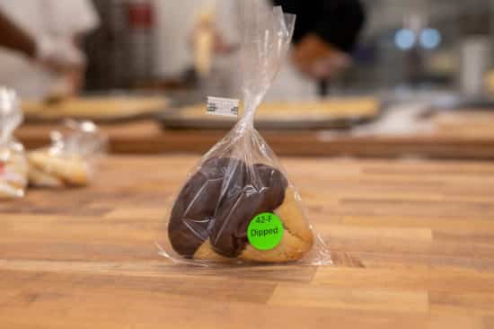 Favor bag with label "42-F Dipped" on it. Two dipped hamantaschen visible inside.