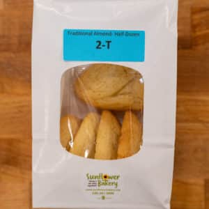 Window bag labeled "Traditional Almond - Half-Dozen 2-T" with traditional almond hamantaschen visible through the window.