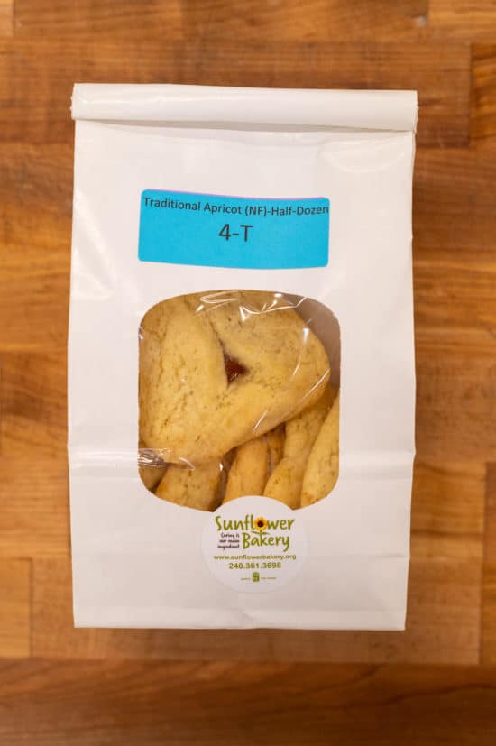 Window bag labeled "Traditional Apricot (NF) - Half-Dozen 4-T" with traditional apricot hamantaschen visible through the window.