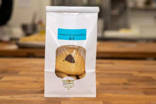 Window bag labeled "Traditional Chocolate (NF) - Half-Dozen 6-T" with traditional chocolate hamantaschen visible through the window.