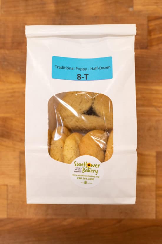 Window bag labeled "Traditional Poppy - Half-Dozen 8-T" with traditional poppy hamantaschen visible through the window.