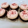 Half-dozen Chocolate Strawberry Cupcakes in a clamshell. Chocolate cake with light pink frosting and freeze dried strawberry powder on top.