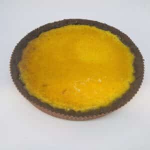 Vivid passion fruit filling in a chocolate tart crust on a white background.