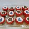 A dozen School Logo Cupcakes with chocolate and vanilla cake, vanilla frosting with a fondant disc with alternating University of Maryland Terrapin mascot or American University logo. All are rolled in red sanding sugar to accent the logo disc.