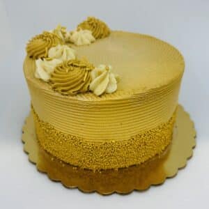 Golden brown cake with gold nonpareils decorating the lower half of the sides of the cake. Half of the top is decorated with alternating swirls of cream and gold frosting, the other space left open.