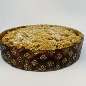 A paper cake pan with a golden brown cake with a crumb topping and a sprinkle of confectioner sugar.