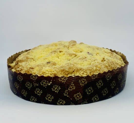 A lemon blueberry streusel cake in a dark brown paper mold on a white background.
