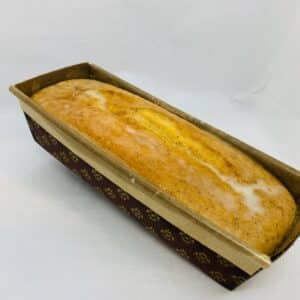 whole loaf of glazed lemon poppy cake in a paper loaf pan