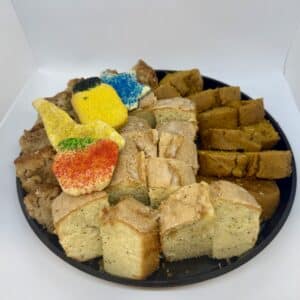 Sliced tea breads on a black platter, decorated with four Rosh Hashanah themed sugar cookies.