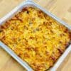 Pan of baked sweet noodle and raisin kugel in an aluminum pan on a wooden counter