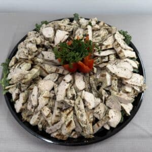 Sliced grilled chicken on a platter with a decorative garnish.